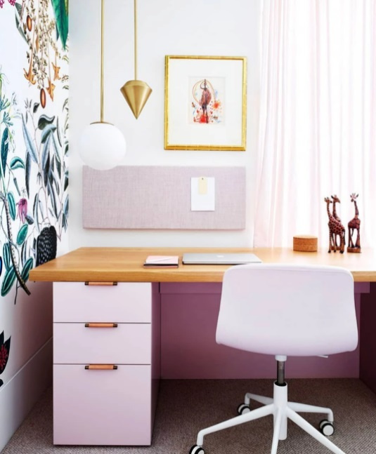 Bureau à domicile avec des meubles rose clair.  Mur avec papier peint botanique