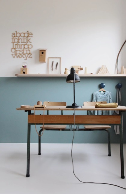 Bureau à domicile avec demi-mur coloré en bleu.  Photos sur l'étagère en bois qui marque la division entre la partie bleue et la partie blanche du mur.  Table en bois.