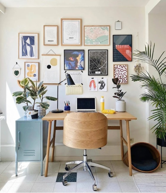 bureau à domicile avec chaise et table en bois.  ordinateur sur la table.  Plantes des deux côtés.  Diverses images sur le mur