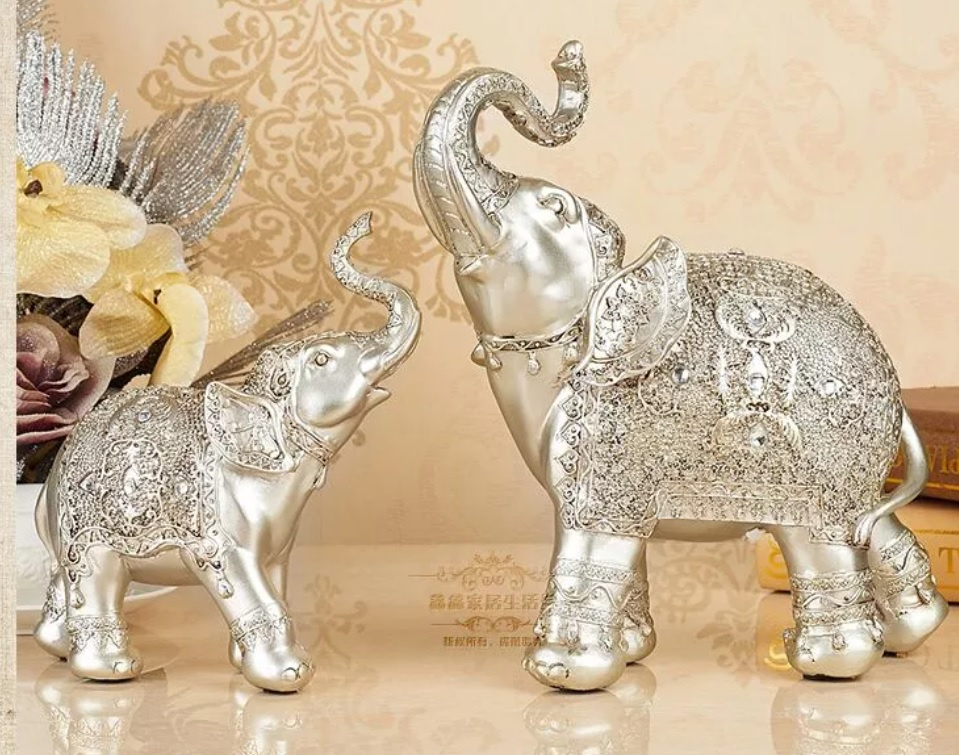 Deux petits éléphants d'argent avec leurs troncs relevés, face à face