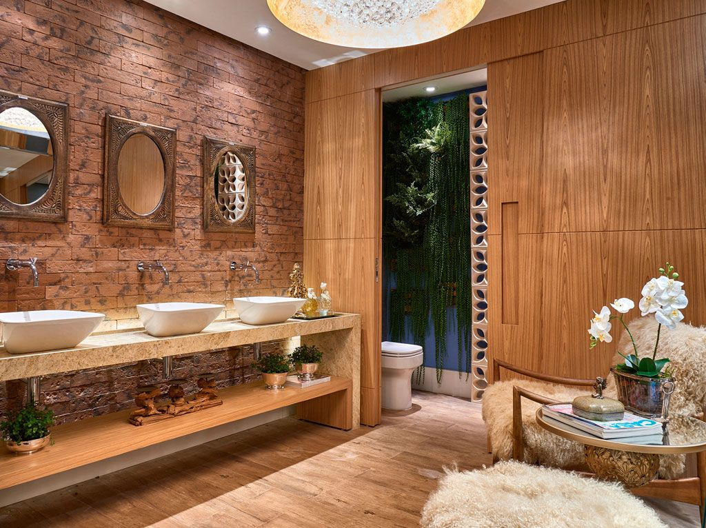 Salle de bain en bois avec mur de briques.  Trois miroirs ronds au-dessus de trois cuves.