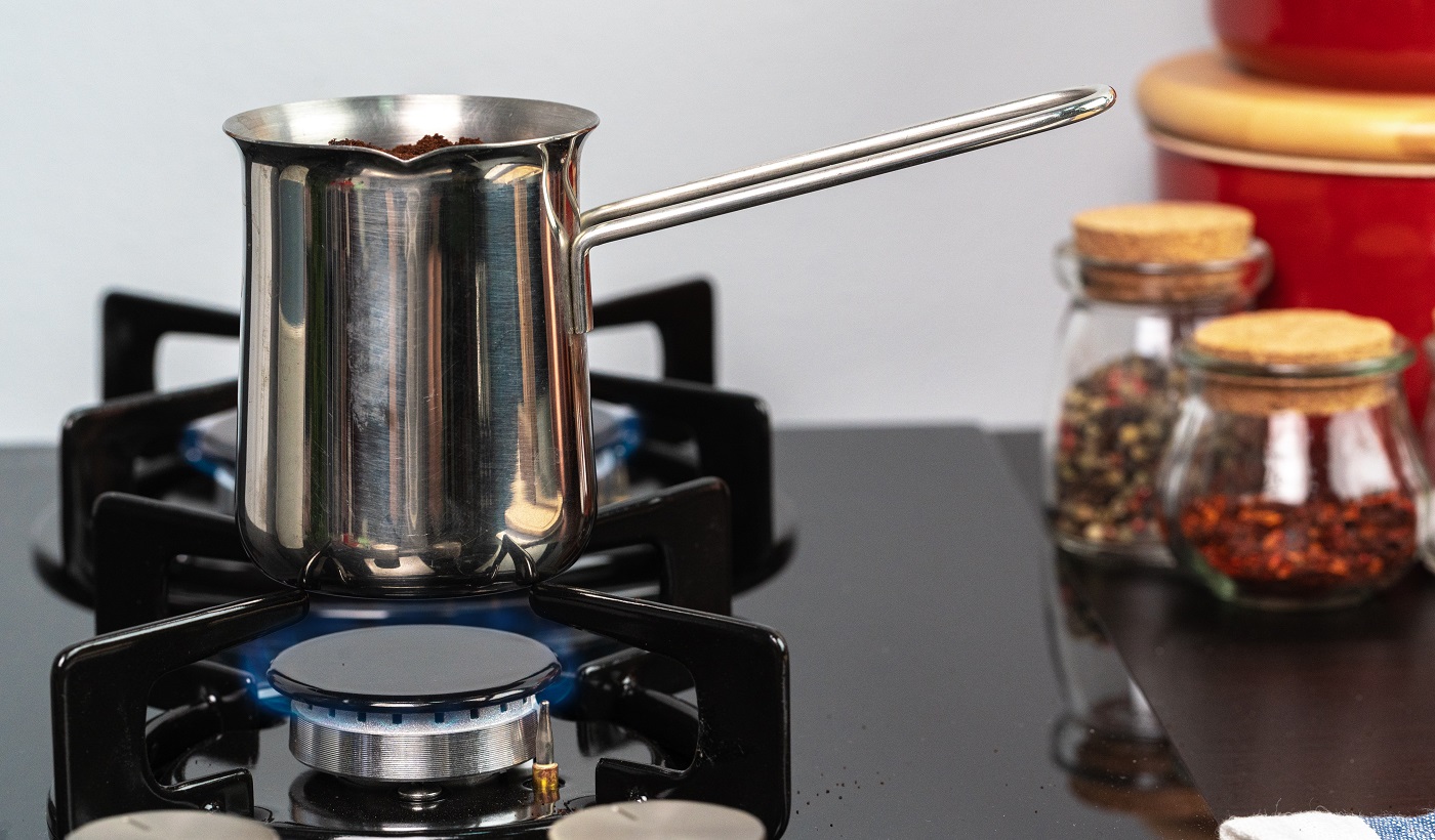Préparez du café dans un turk en acier sur une cuisinière à gaz close up