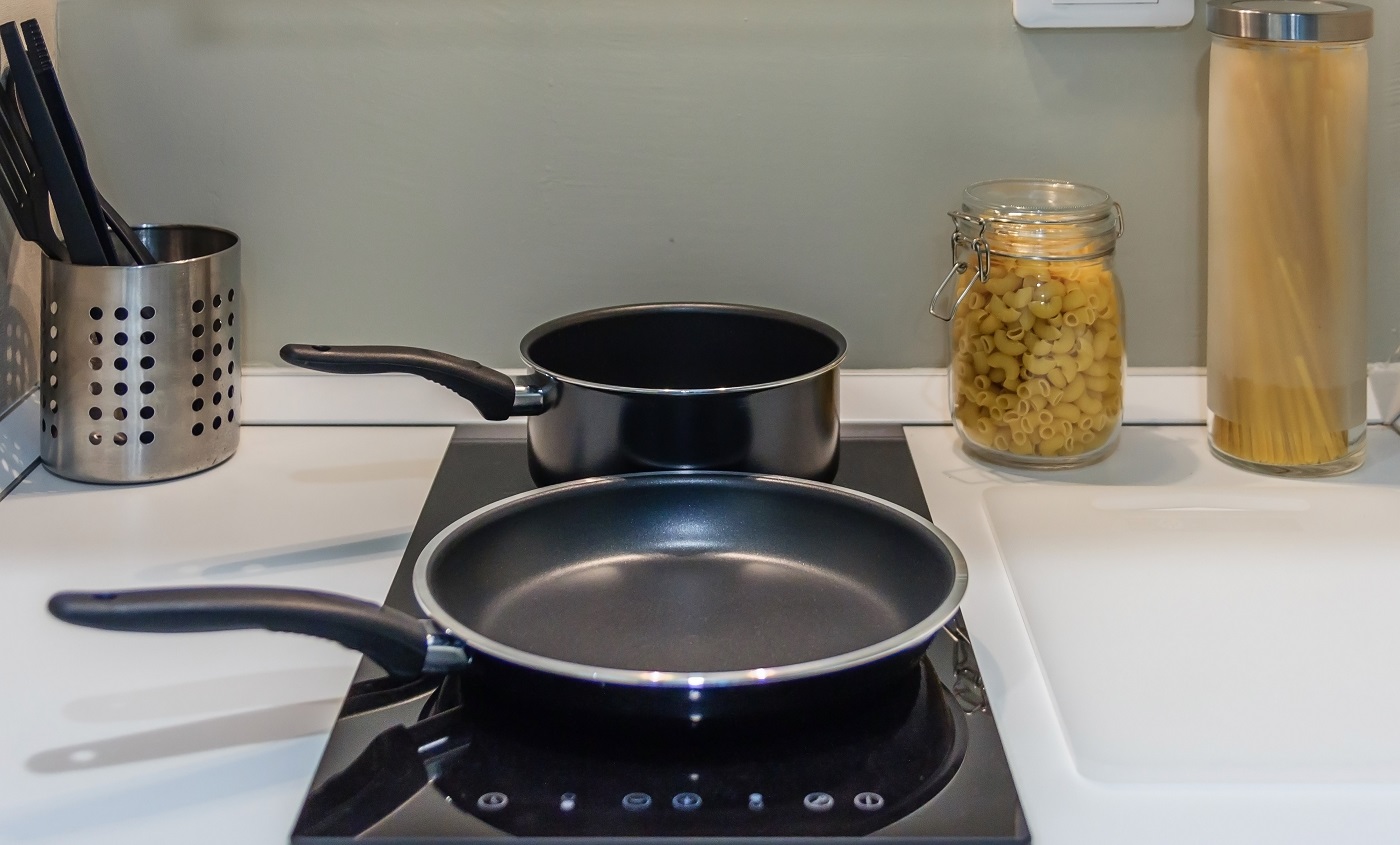Casserole noire sur le panneau supérieur de la cuisinière à induction dans la cuisine moderne pour la cuisson, gros plan