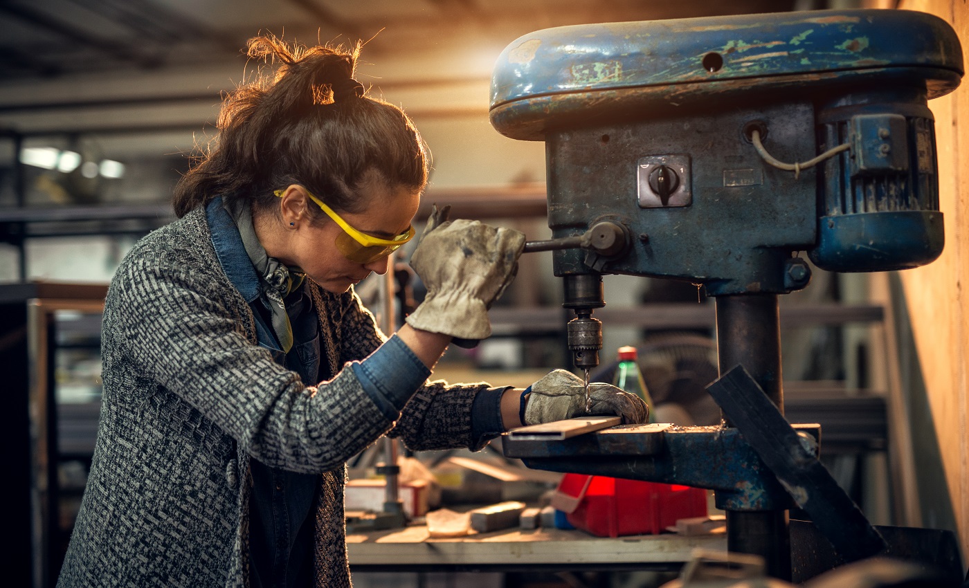 Vue portrait d'une menuiserie professionnelle sérieuse d'âge moyen travaillant avec une perceuse électrique dans l'atelier.