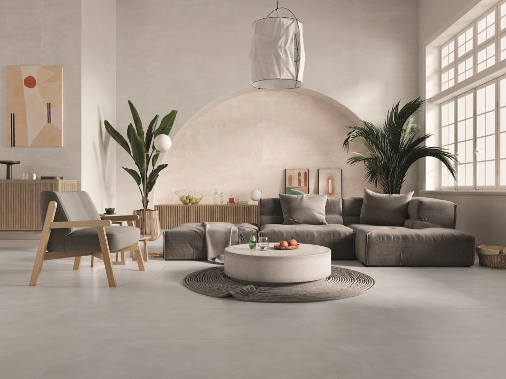 Salon avec sol en ciment brûlé, canapé gris et fauteuil