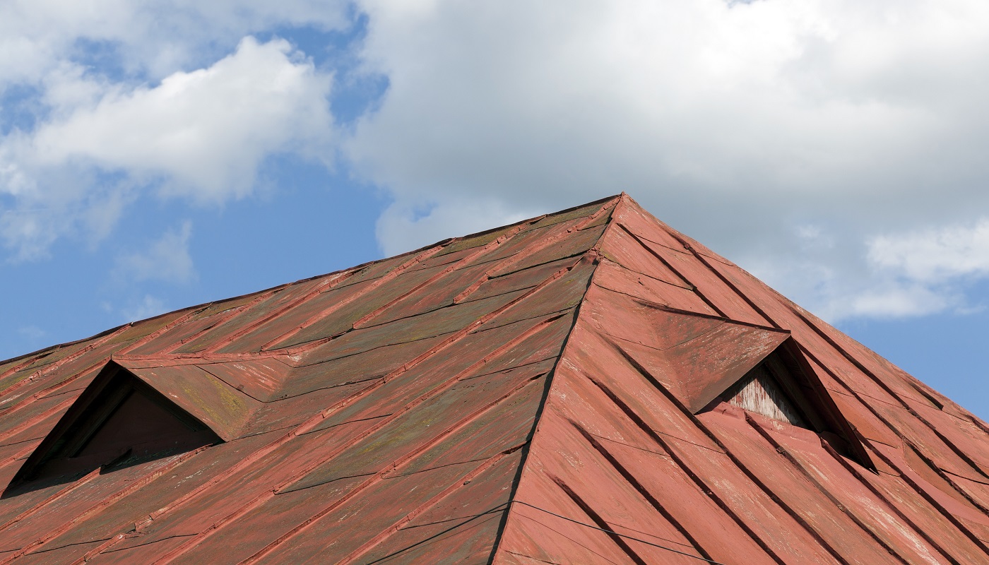 vieux toit en métal rouge du bâtiment contre le ciel bleu, beaucoup de dégâts sur le métal, gros plan