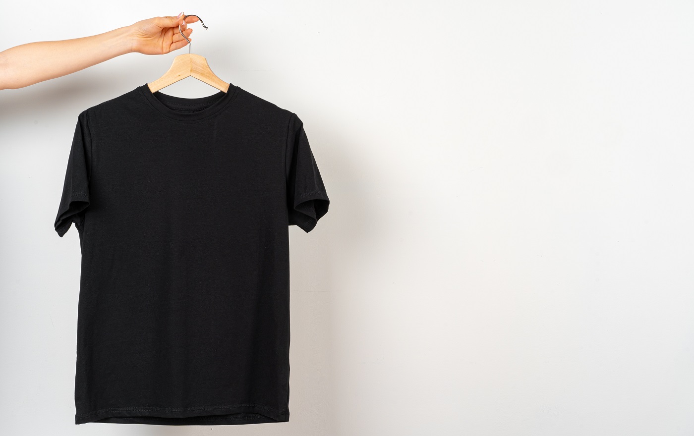 T-shirt uni noir accroché à un cintre, espace copie