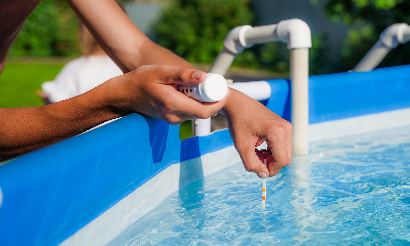 Vérification de la qualité de l'eau d'une piscine à l'aide d'une bandelette réactive avec valeur PH, chlore et algicide.  photo de haute qualité