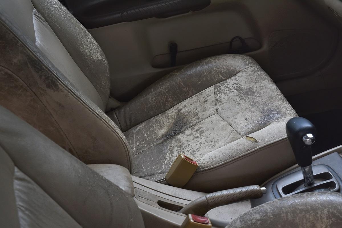Siège de voiture en cuir fissuré et endommagé, gros plan de l'intérieur de la vieille voiture de rembourrage sale.  Comment réparer une déchirure de siège de voiture en cuir.