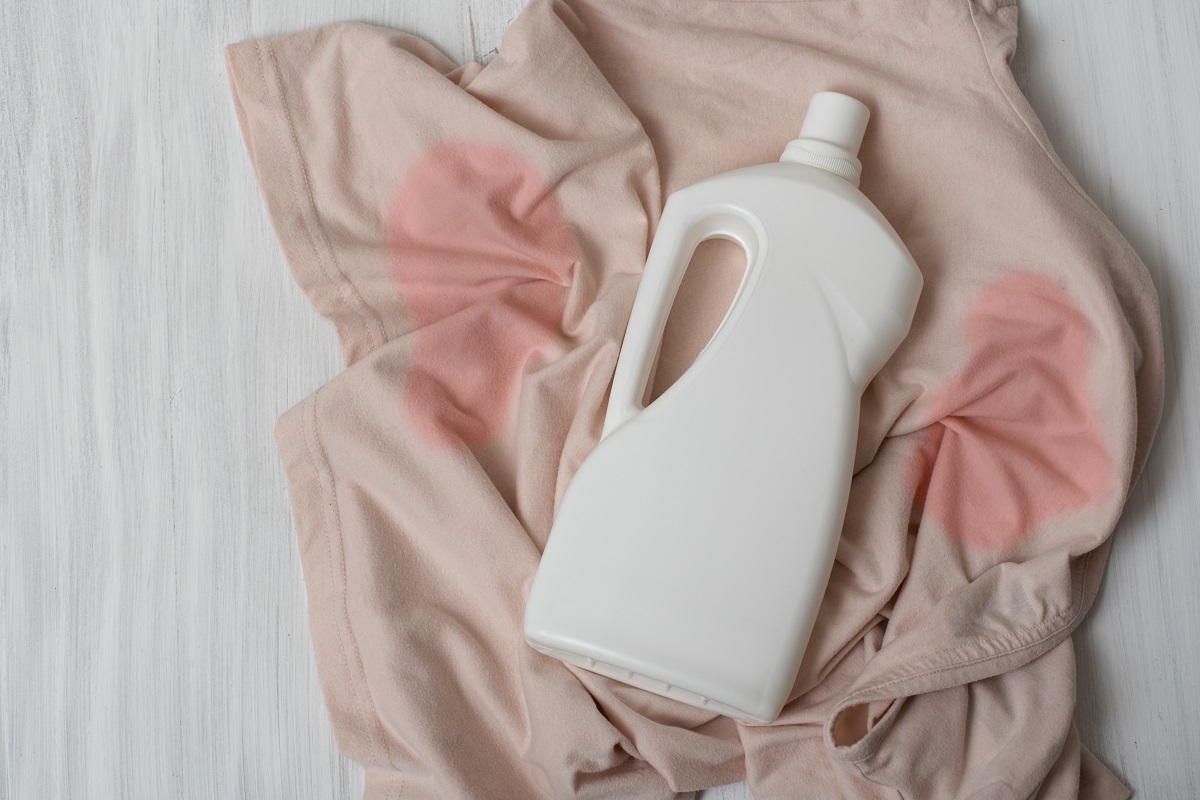 Des vêtements avec des taches et une bouteille de détergent.  Vue de dessus.  Est-ce que les peintures acryliques se lavent.