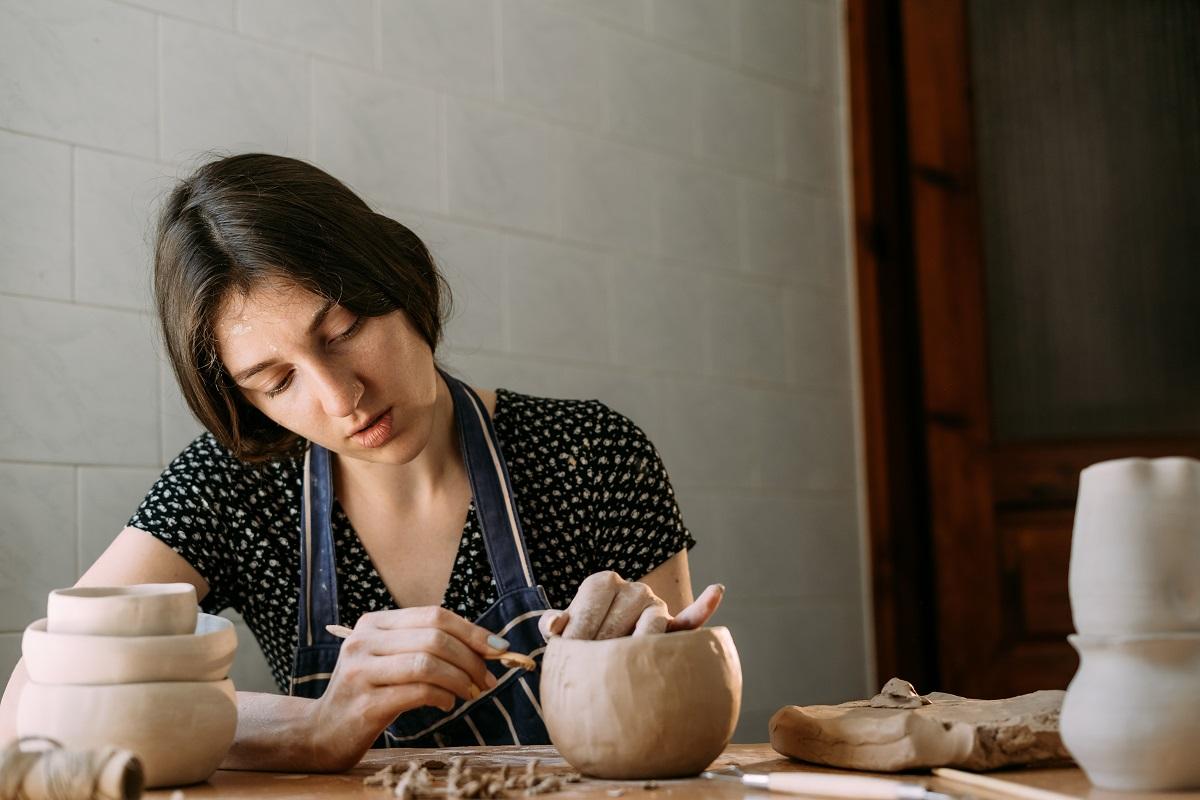 Une fille arménienne fabrique un produit en argile.  Modelage dans un atelier à la maison.  Créativité et fait main.  Pot en argile entre les mains d'une femme avec un outil.  Concept d'art et de texture.  Pot en terre cuite.
