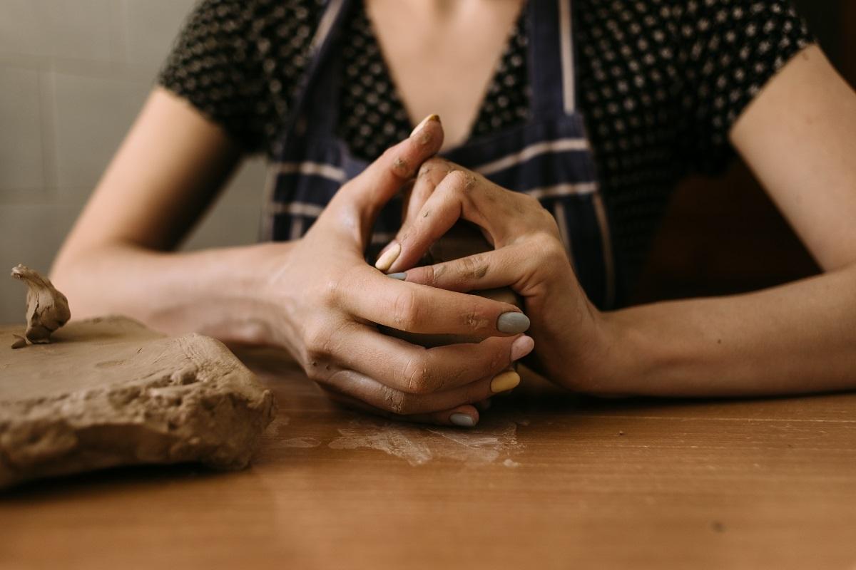 gros plan Les mains d'une femme sculpteur pétrissent l'argile sur la table à la maison.  Modelage d'argile passe-temps.  Principaux types d'argile à sculpter.