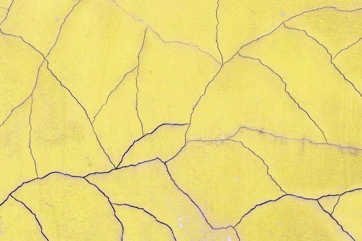Gros plan surface ancienne et fond de texture de mur de ciment jaune craquelé.  Pourquoi le béton se fissure.