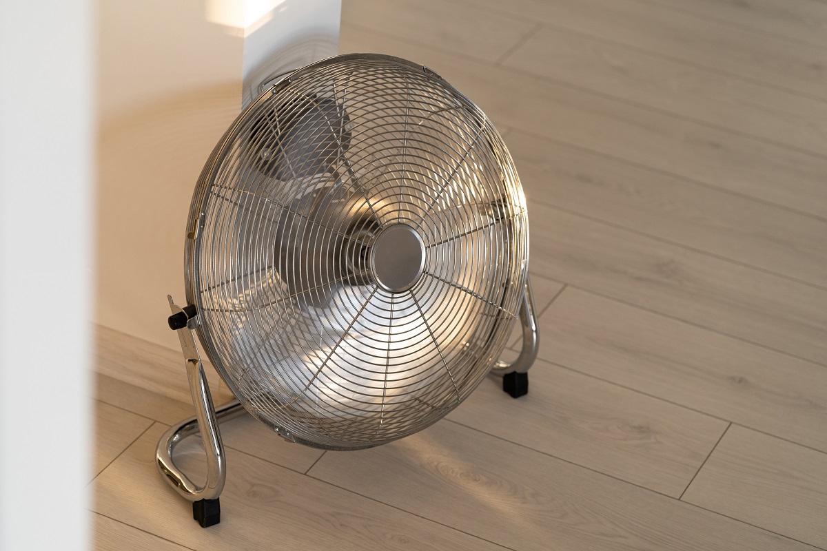 Ventilateur de ventilation en métal argenté sur parquet à la maison.  Ventilateur de sol à grande vitesse Lasko.
