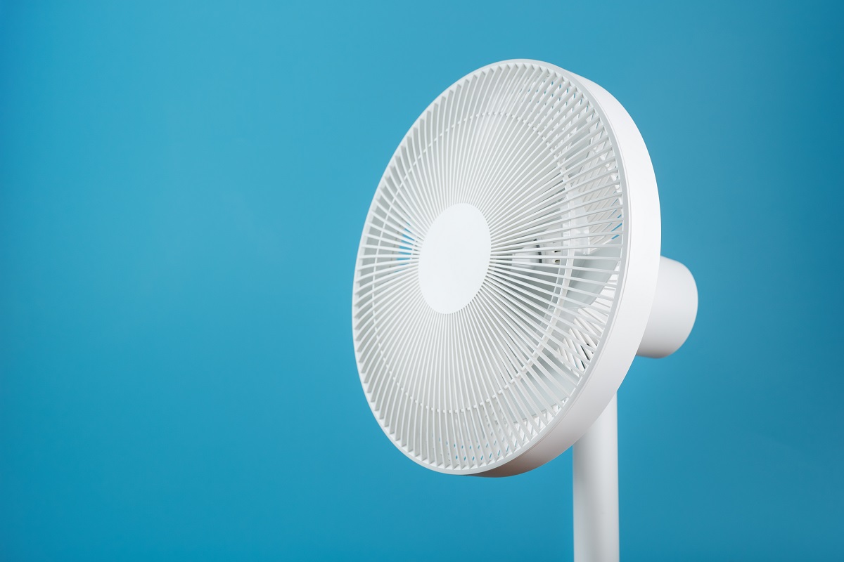 Ventilateur électrique blanc au design moderne pour rafraîchir la pièce sur fond bleu.  Espace libre, style minimaliste.  Raisons derrière le ventilateur soufflant de l'air chaud.