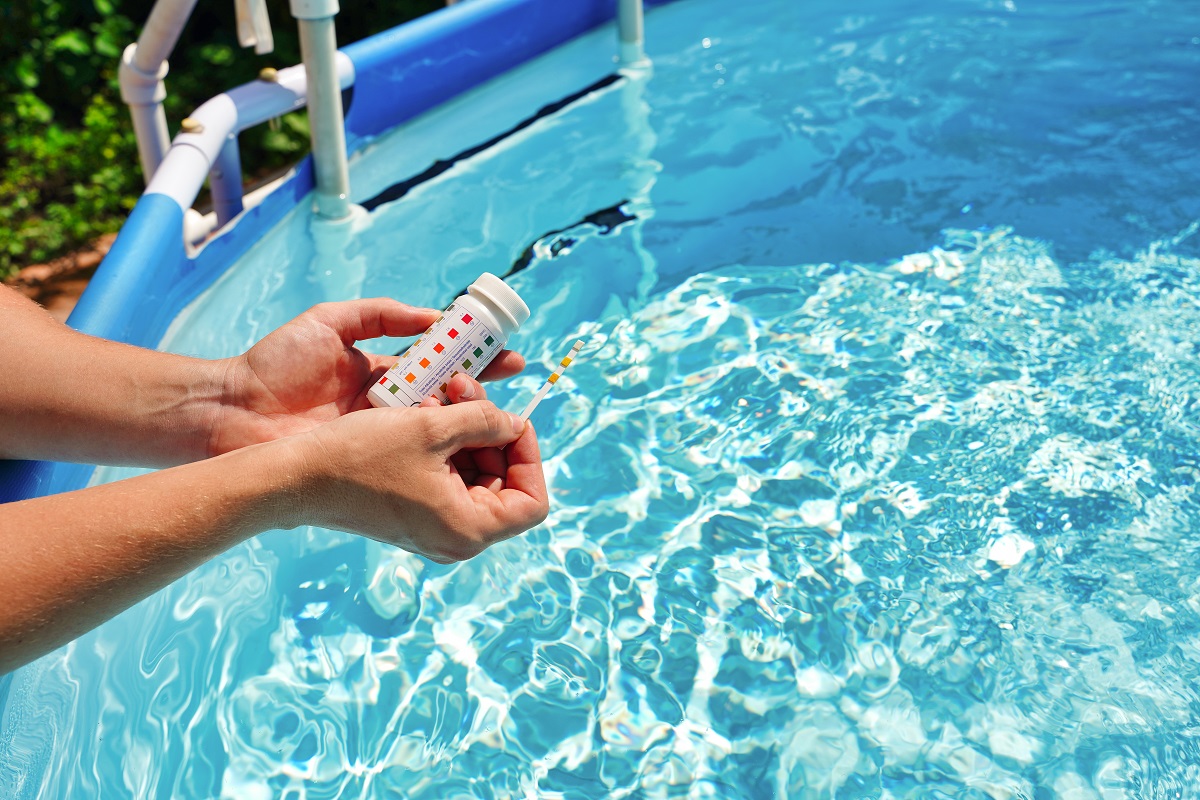 Vérification de la qualité de l'eau d'une piscine à l'aide d'une bandelette de test avec valeur PH, chlore et algicide.  Photo de haute qualité.  Les bandelettes de test de piscine sont-elles bonnes?