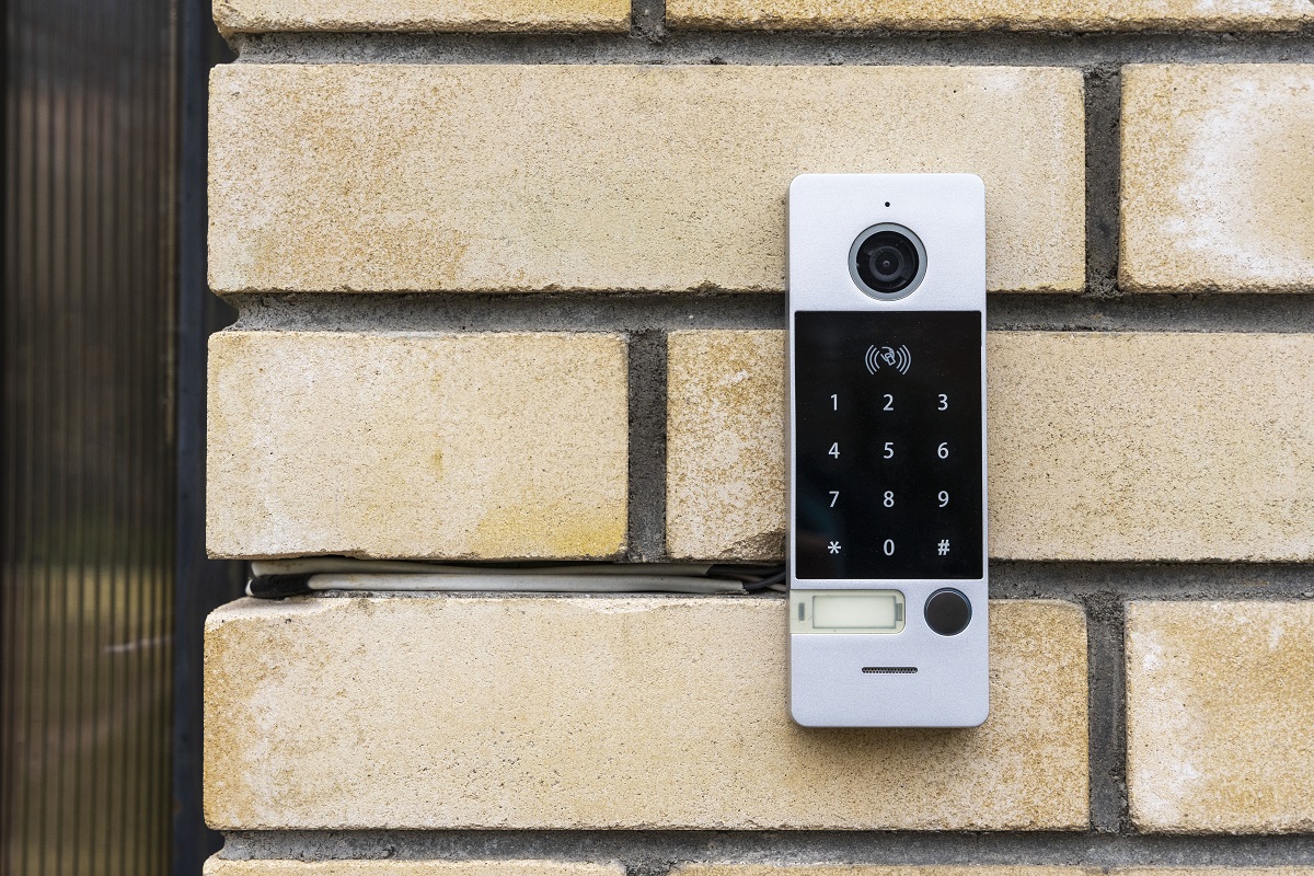 un interphone à la porte d'une maison privée, un panneau d'interphone avec une caméra vidéo sur un poteau de clôture beige brique d'une maison privée.  Ring Video Doorbell Pro et Basic.